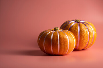 Pumpkins on pastel pink background with pastel ribbon. Autumn, fall, halloween concept.