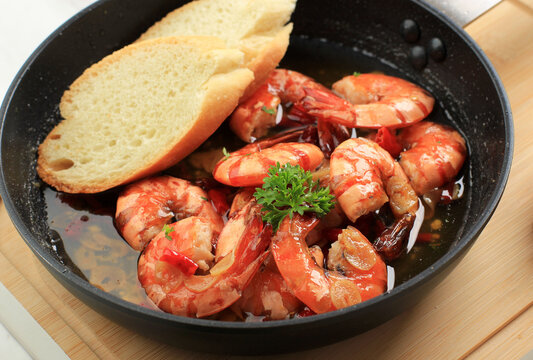 Close Up Spanish Gambas with Oil (Ajillo). Shrimp Scampi. Traditional Spanish Tapa with Prawns Cooked in Oil with Garlic and Chilli. Served with Slice Baguette