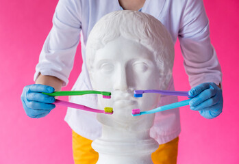 Woman dentist brushing teeth of an antique statue using a four toothbrushes