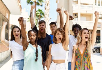 Group of young activists protesting with fists raised up standing at the city.