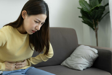 Asian woman sick at home. Woman touch stomach, stomach ache, food allergy, menstrual pain or stomach ache from colon cancer