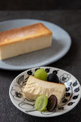 皿に乗ったカットしたチーズケーキとシャインマスカット、巨峰