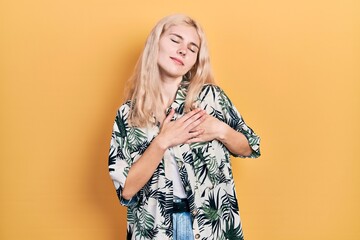 Beautiful caucasian woman with blond hair wearing tropical shirt smiling with hands on chest with closed eyes and grateful gesture on face. health concept.