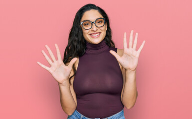 Brunette young woman wearing casual clothes and glasses showing and pointing up with fingers number ten while smiling confident and happy.