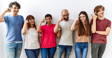 Group of young friends standing together over isolated background smiling pointing to head with one finger, great idea or thought, good memory