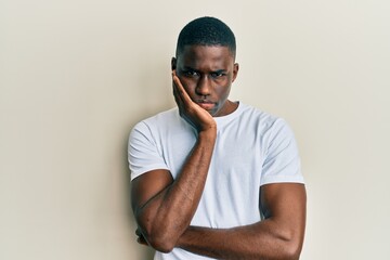 Young african american man wearing casual white t shirt thinking looking tired and bored with...
