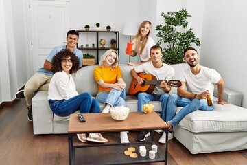 Group of young friends on party smiling happy and playing classical guitar at home.