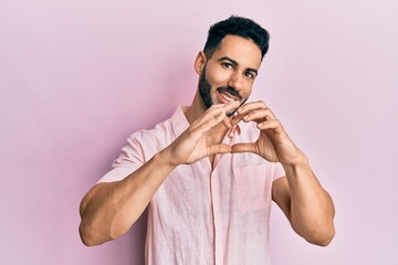 Naklejka premium Young hispanic man wearing casual clothes smiling in love showing heart symbol and shape with hands. romantic concept.