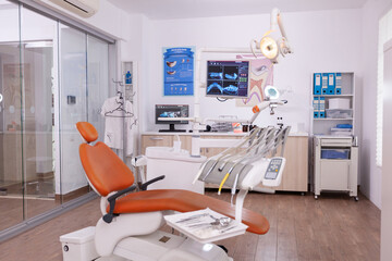 Empty modern orthodontic stomatology hospital light office with nobody in it equipped with dental intruments ready for teeth healthcare treatment. Tooth radiography images on display