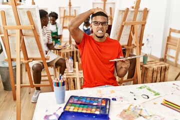 Young african man at art studio stressed and frustrated with hand on head, surprised and angry face