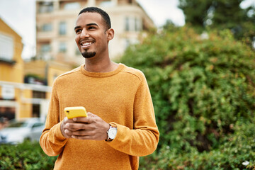 Young african american man smiling happy using smartphone at the city.