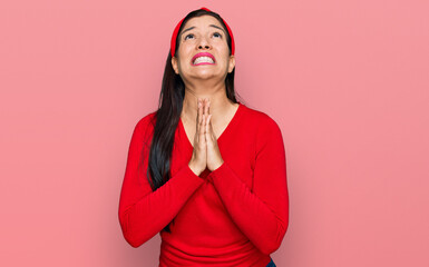 Young hispanic woman wearing casual clothes begging and praying with hands together with hope...