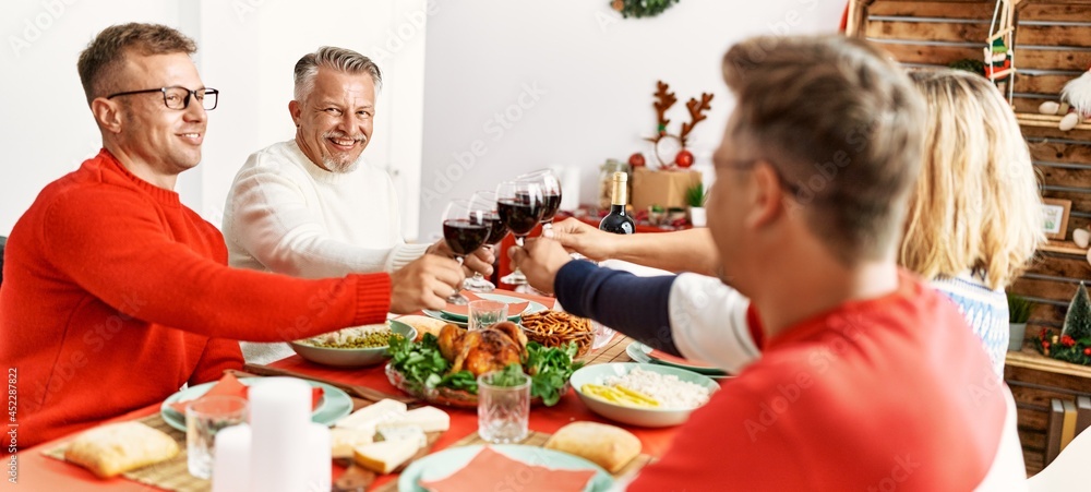 Sticker Group of middle age people smiling happy having christmas dinner toasting with wine at home.