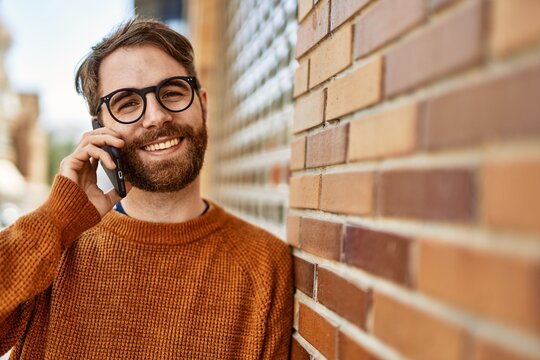 Caucasian man with beard having a conversation speaking on the phone outdoors on a sunny day