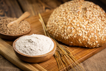 Delicious fresh bread on a wooden board with flour and wheat.