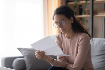 Serious entrepreneur freelancer woman wear glasses reading attentively paper letter official...
