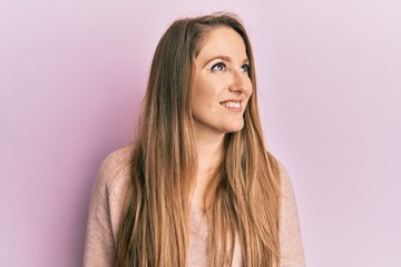Fototapeta premium Young blonde woman wearing casual sweater looking away to side with smile on face, natural expression. laughing confident.