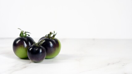 Fresh black cherry tomatoes on white background