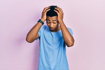 Young african american man wearing casual blue t shirt suffering from headache desperate and stressed because pain and migraine. hands on head.