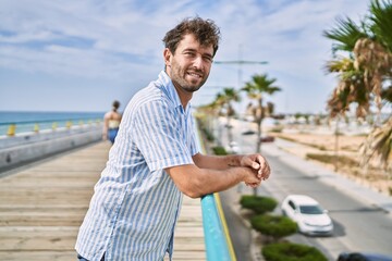 Young hispanic man smiling happy standing at the promenade.