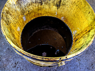 old dirty bucket with used engine oil in the garage.