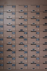 Mailboxes room in an apartment or condominium building.  Rows of numbered wooden mailboxes and lock at Entrance. Post box of apartments for check the mail.