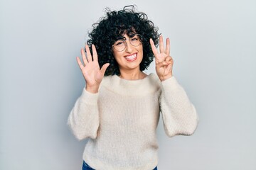 Young middle east woman wearing casual white tshirt showing and pointing up with fingers number eight while smiling confident and happy.