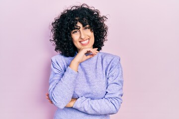 Young middle east woman wearing casual clothes looking confident at the camera with smile with crossed arms and hand raised on chin. thinking positive.