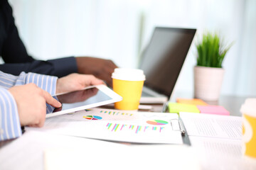 Image of two young businessmen using touchpad at meeting