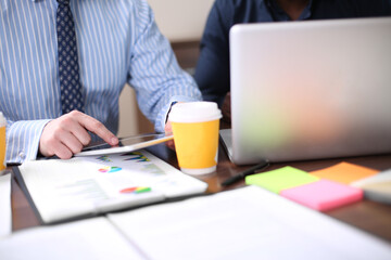 Image of two young businessmen using touchpad at meeting