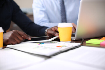 Image of two young businessmen using touchpad at meeting