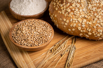 Delicious fresh bread on a wooden board with flour and wheat.