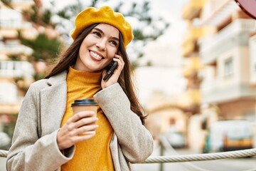 Young hispanic girl talking on the smartphone drinking coffee at the city.
