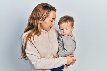 Young caucasian woman holding and hugging her son with love. Family of two bonding together. Mother holding infant toddler