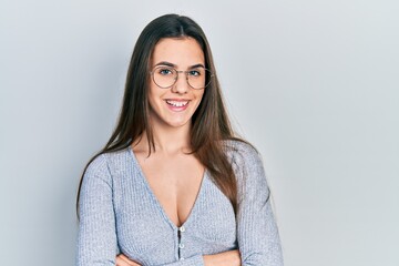 Obraz premium Young brunette teenager wearing casual sweater and glasses happy face smiling with crossed arms looking at the camera. positive person.