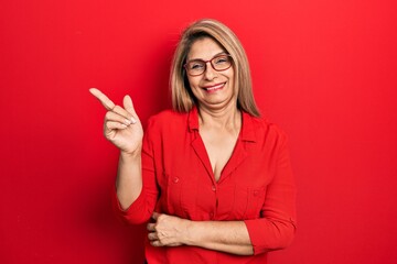 Middle age hispanic woman wearing casual clothes and glasses smiling happy pointing with hand and finger to the side