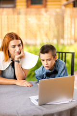 child boy and mother listing to a lecture , is using a laptop and communicates on the Internet at home. homeschooling, distant learning, online e