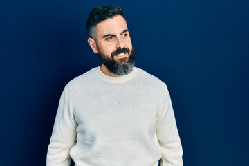 Young hispanic man wearing casual clothes looking away to side with smile on face, natural expression. laughing confident.