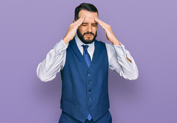 Young man with beard wearing business vest with hand on head for pain in head because stress. suffering migraine.