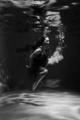 Obraz na płótnie Canvas Beautiful girl underwater in the pool. Black and white photography, creative and mystical