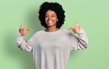 Young african american woman wearing casual clothes looking confident with smile on face, pointing...