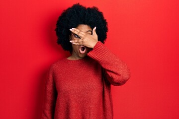 Fototapeta na wymiar Young african american woman wearing casual clothes and glasses peeking in shock covering face and eyes with hand, looking through fingers afraid