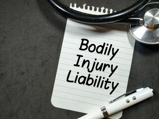 Medical concept.Text Bodily Injury Liability writing on notepaper with pen and stethoscope on black...
