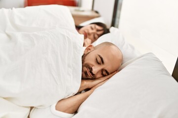 Young hispanic couple sleeping on the bed at bedroom.