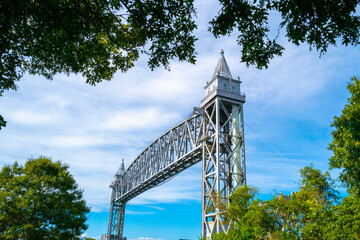 Cape Cod Canal Railway Bridge behind green trees on cloudy blue sky background
