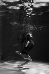 Obraz na płótnie Canvas Beautiful girl underwater in the pool. Black and white photography, creative and mystical
