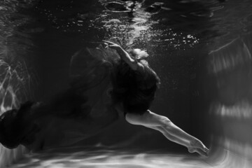 Beautiful girl underwater in the pool. Black and white photography, creative and mystical