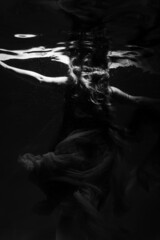 Beautiful girl underwater in the pool. Black and white photography, creative and mystical