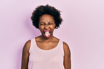Young african american woman wearing casual sleeveless t shirt sticking tongue out happy with funny expression. emotion concept.