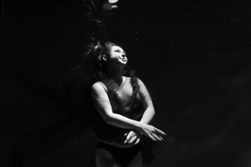 Beautiful girl underwater in the pool. Black and white photography, creative and mystical